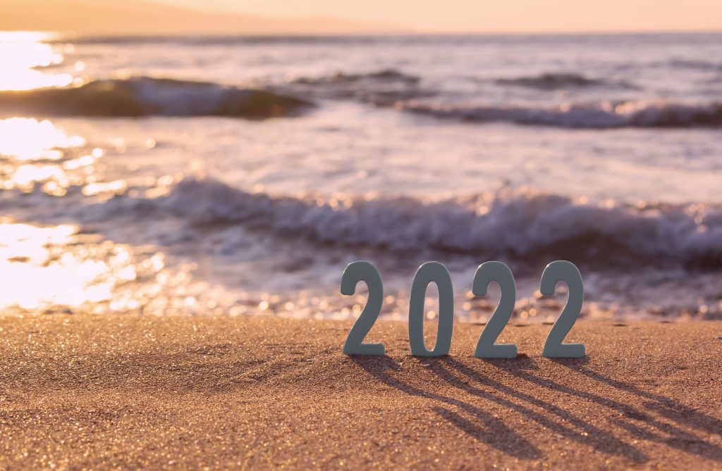 2022 numbers sitting in sand with waves behind it