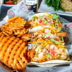 Fish tacos and waffle fries on a plate.
